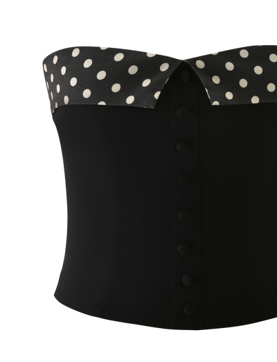 The TIGERMIST KITTIE 2.0 BUSTIER - BLACK is a strapless corset in suiting fabric, featuring fabric-covered front buttons and a stylish black and white polka dot collar detail.