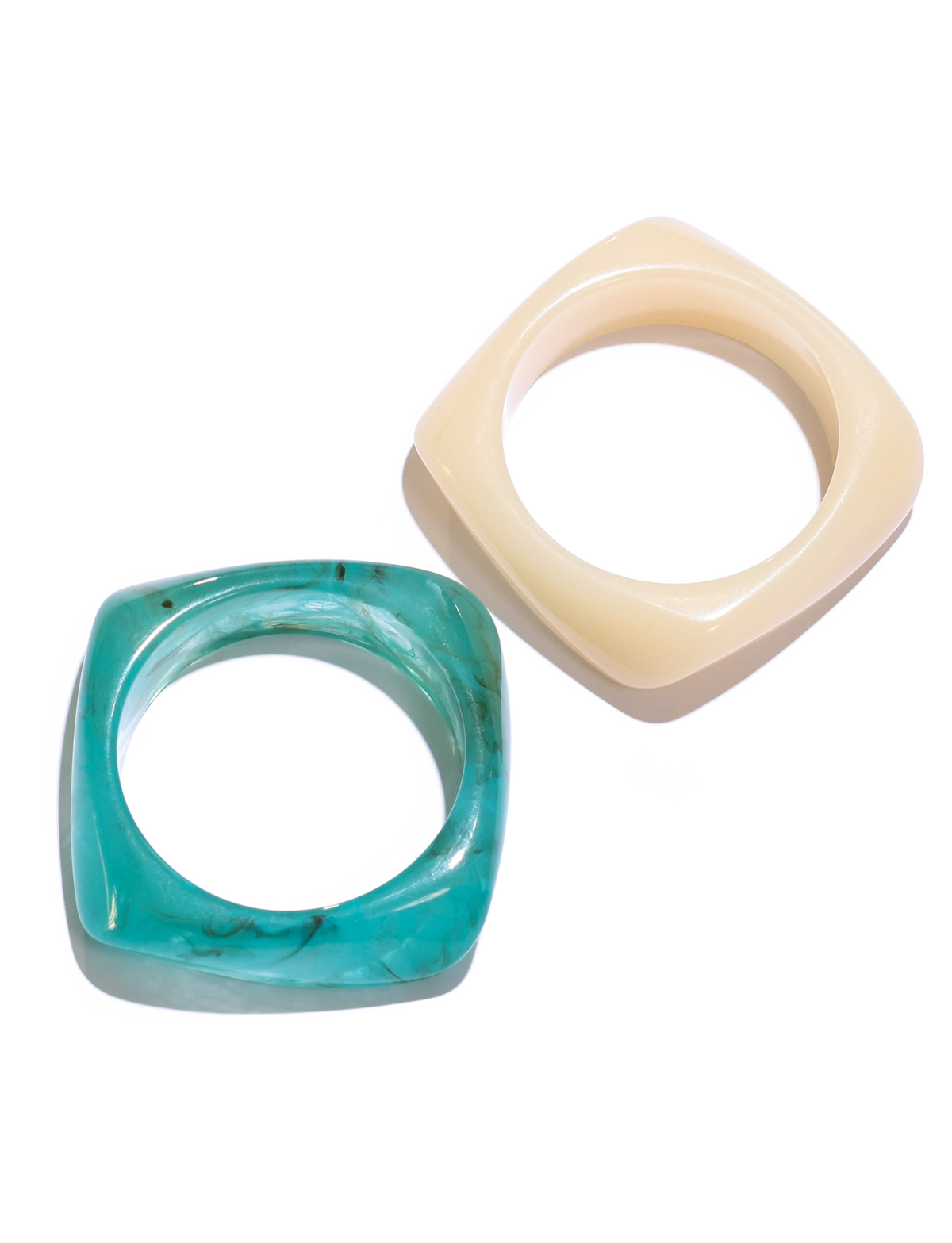 The TIA CHUNKY 2PC RESIN BANGLE SET by TIGERMIST features two square-shaped bangles—one with a marble-like blue finish and one in glossy cream, both with circular openings—displayed on a white background.