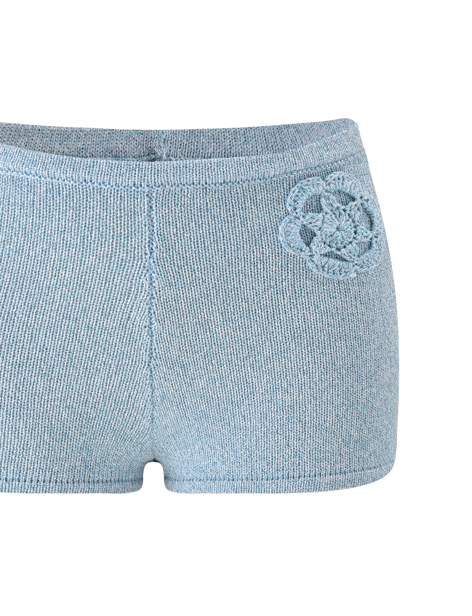 The SUNIA SHORT - BLUE by TIGERMIST is an ultra-mini light blue hot short with a decorative crocheted flower appliqué on the left hip, featuring a seamless, simple design and displayed on a white background.