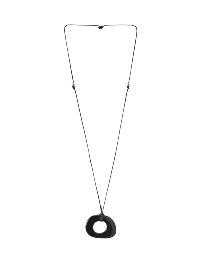 The FAELLA PENDANT NECKLACE - BLACK by TIGERMIST features a long, thin adjustable cord with two small beads and a large smooth black resin pendant with an off-center hole, shown against a plain white background.