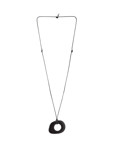 The FAELLA PENDANT NECKLACE - BLACK by TIGERMIST features a minimalist, irregular black resin pendant with a central hole on an adjustable cord, shown against a plain white background.