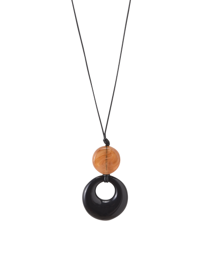The TIGERMIST BREYA PENDANT NECKLACE - TAN features a minimalist black cord with a tortoiseshell bead and a circular black resin pendant with a central hole, displayed against a plain white background.