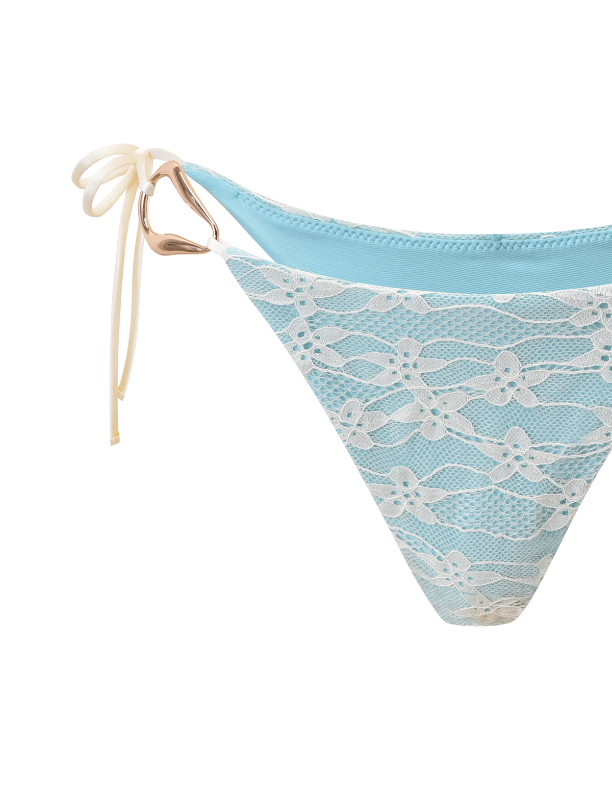 The SIKA BIKINI BOTTOM - BLUE LACE by TIGERMIST features a light blue lace design, cheeky cut, white side tie, and a gold heart-shaped ring detail. Shown against a plain white background.