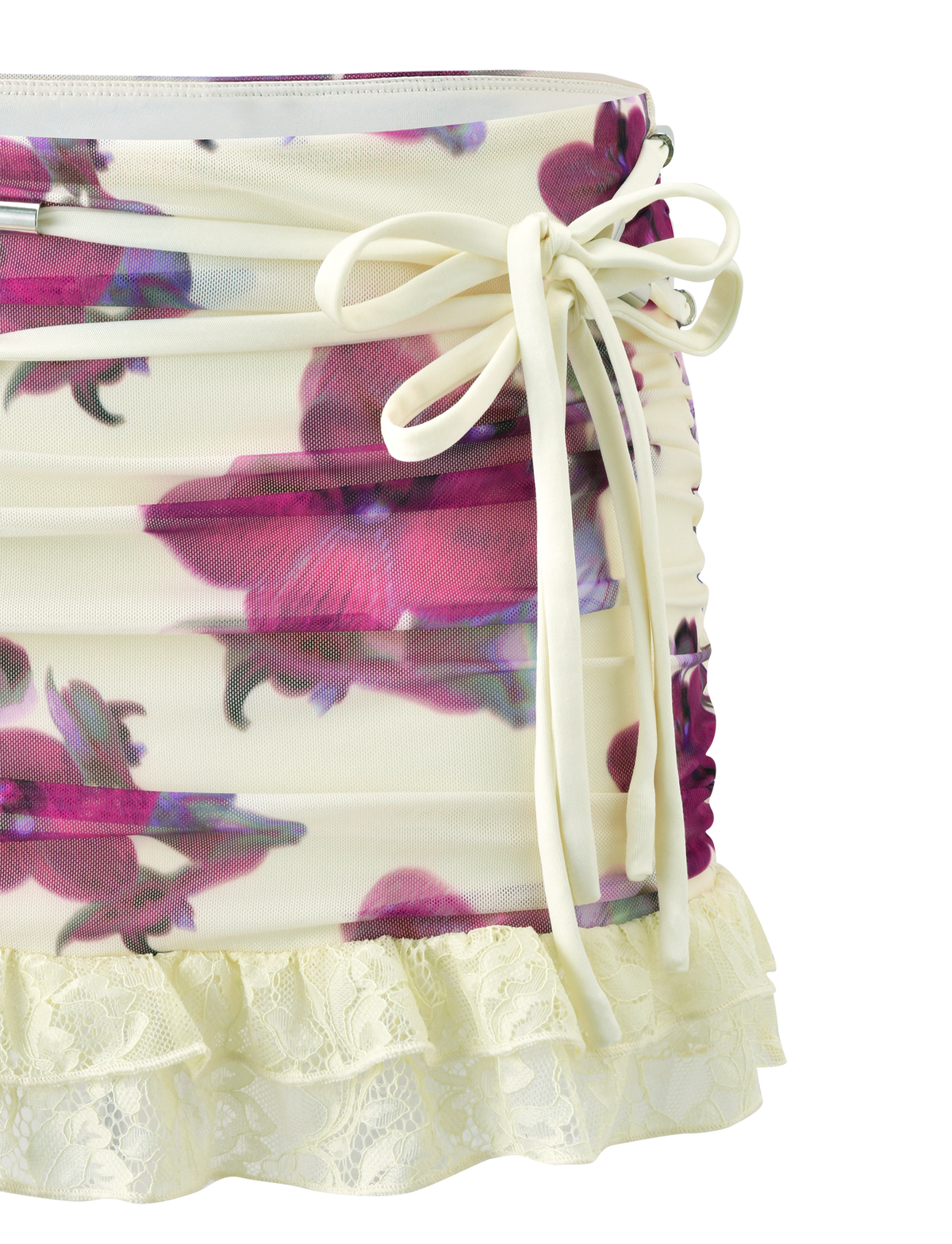 The LILIAH MINI SKIRT - ORCHID HAZE by TIGERMIST features cream fabric, side ruching, a bow tie accent, vibrant orchid print, and a frilled lace hem.