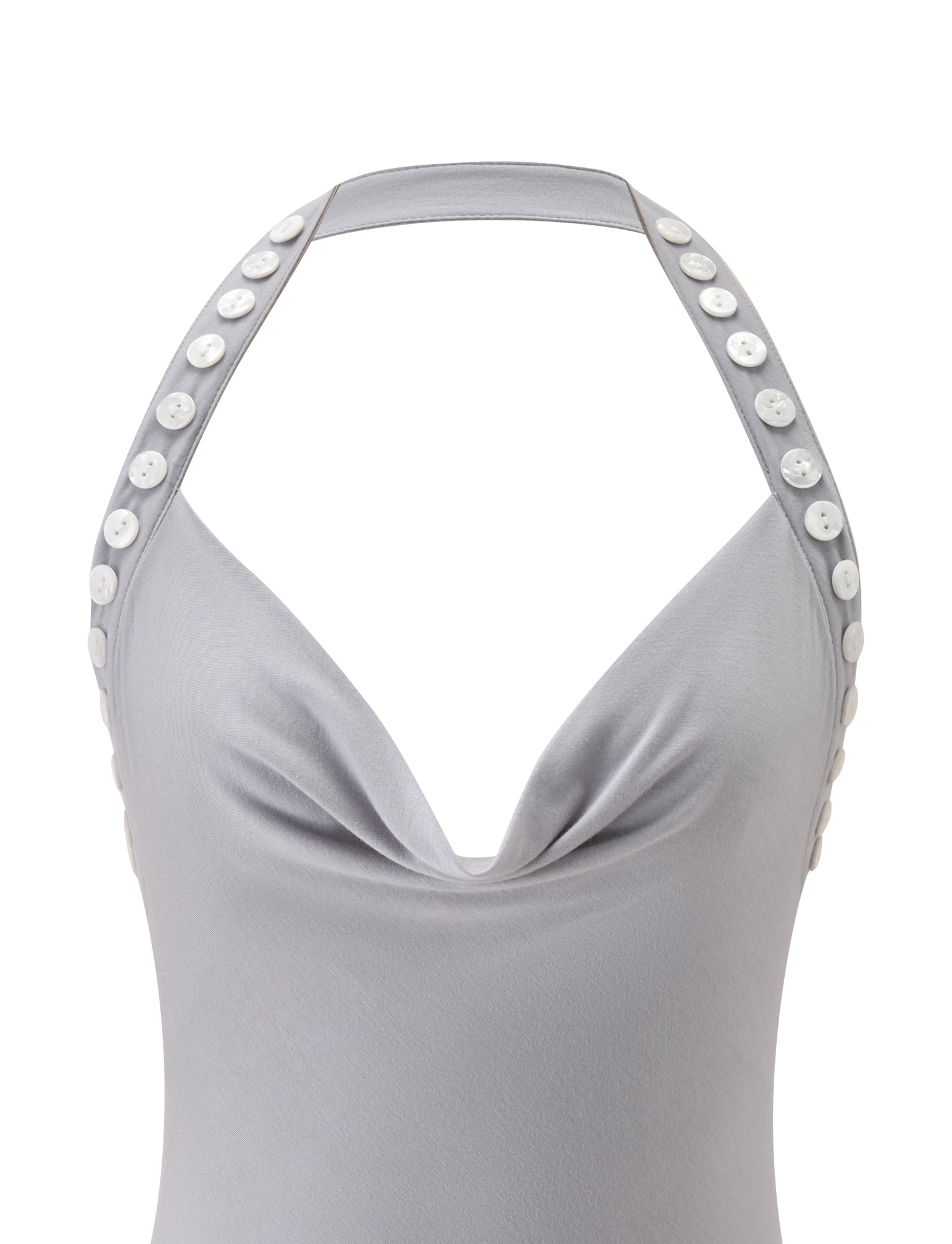 Introducing the SUKI TOP - GREY by TIGERMIST: a light gray halter neck top crafted from buttery-soft jersey, featuring a fashionable cowl neckline and two straps detailed with white buttons along the edges. Finished with an asymmetrical hem, this modern grey cowl neck top is both stylish and unique.