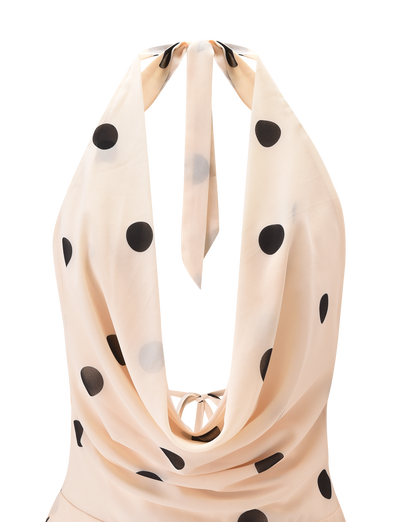 The TIGERMIST LATHAN MINI DRESS in cream is a chiffon halter mini dress with black polka dots, a draped neckline, neck tie, and a tiered flounce skirt.