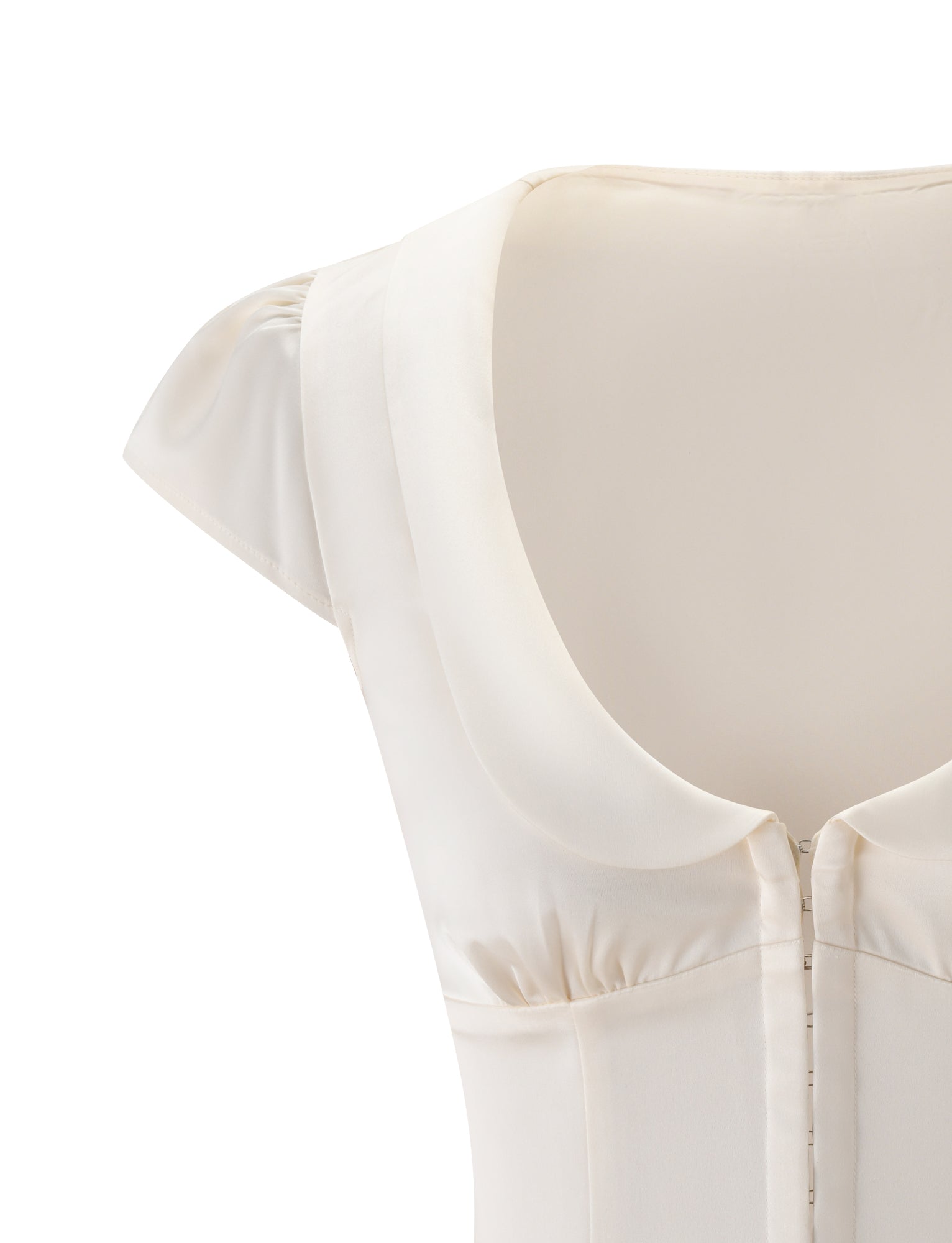 Close-up of the MAURA TOP in white by TIGERMIST, featuring a wide rounded collar, cap sleeves, princess seams on the fitted bodice, and front button or snap closures. The material appears smooth and slightly shiny, possibly satin or silk.