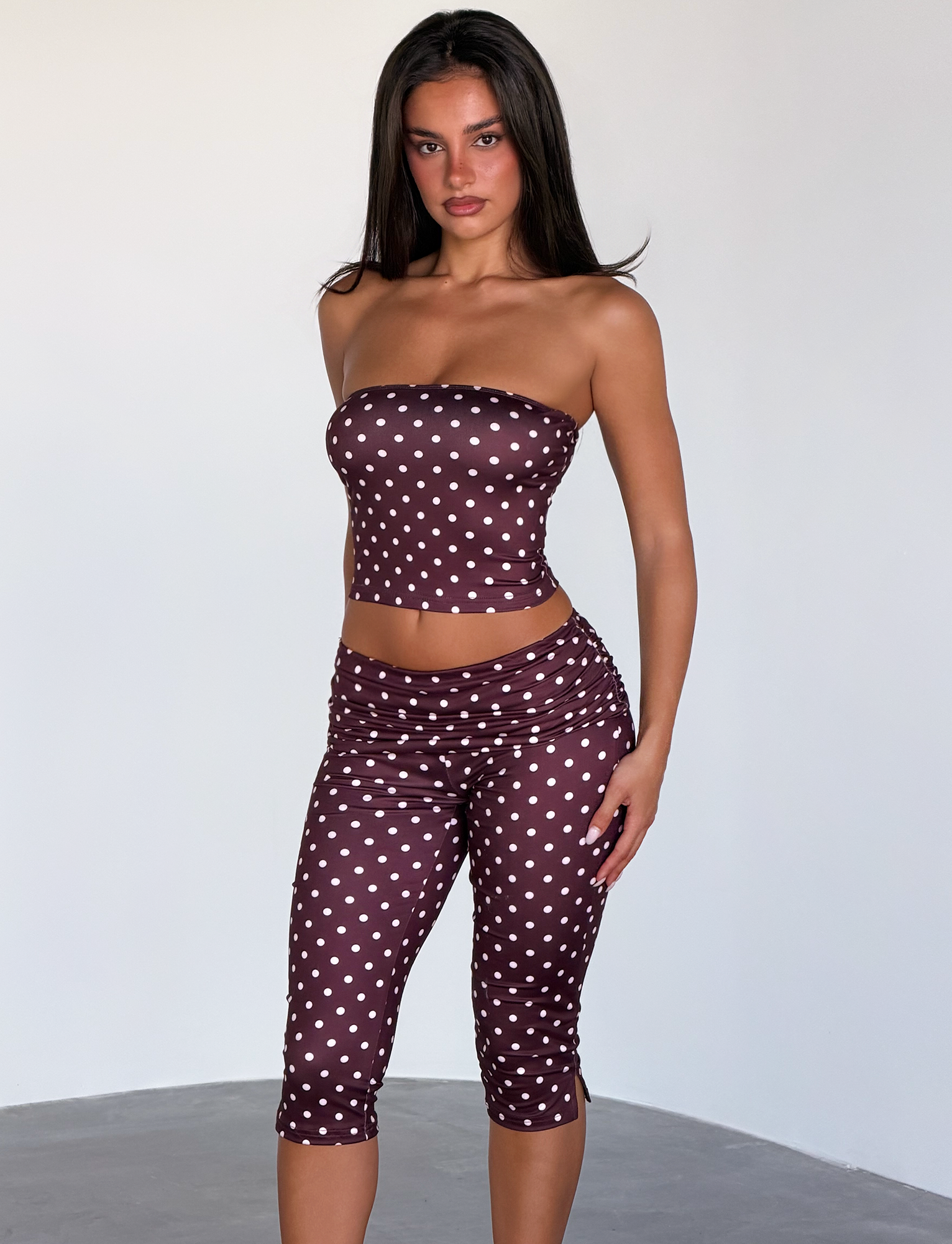 Wearing the TIGERMIST VALI Polka Dot Top in Chocolate Pink Dot, a woman stands against a light background, looking directly at the camera.