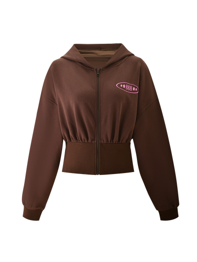The TIGERMIST MERRYN HOODIE - CHOCOLATE is a brown zip-up cropped hoodie with long sleeves, a hood, ribbed cuffs, wide waistband, and a pink "888" puff print with small stars on the left chest.