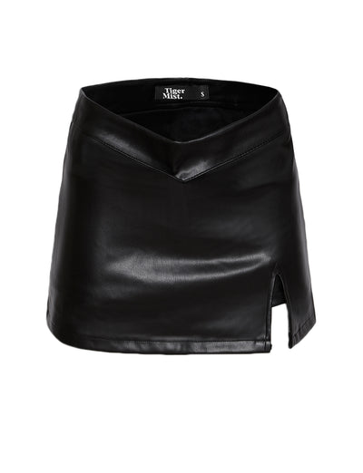 This chic skort from TIGERMIST, named the DAPHNIE PU SKORT – BLACK, features a high waistline and a small front slit on the right side. The waistband has a subtle pointed V-shape at the front, adding to its stylish design. Inside, the label reads "Tiger Mist" with the size "S.