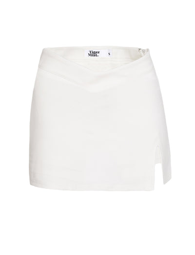 The DAPHNIE SKORT - WHITE by TIGERMIST is a mini-length skort featuring a subtle V-shaped waistband and a small slit on the right side. Made from smooth fabric, it offers a mid-rise fit and includes an internal label with "Tiger Mist" and size "S.