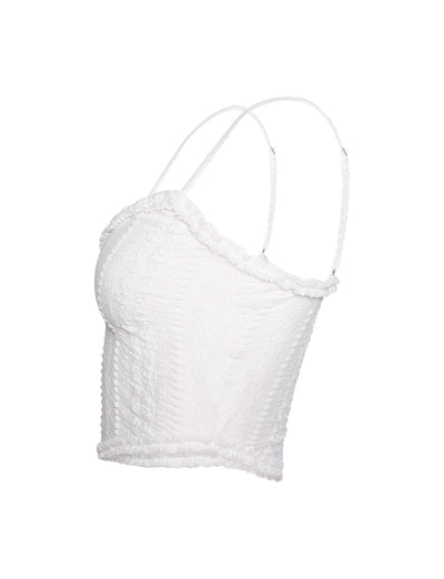 A side view of the SOPHA TWO PIECE TOP - WHITE by TIGERMIST reveals a textured, sleeveless crop top with thin spaghetti straps, featuring slight ruffle detailing along the neckline and hem.