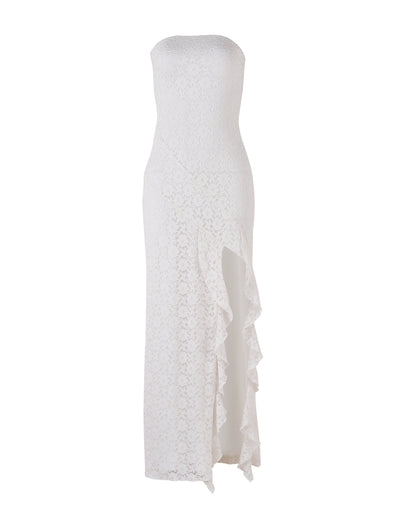 The TIGERMIST THEO LACE MAXI DRESS - WHITE is a strapless, floor-length white lace dress with a fitted silhouette. It features a delicate floral pattern throughout and an asymmetrical, stylish ruffle cascading down from the high slit on the left side.